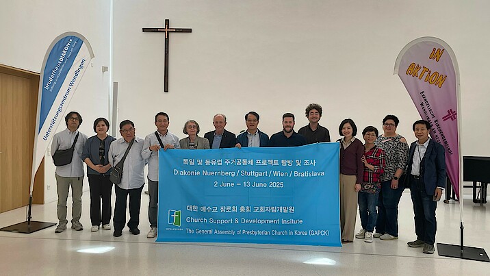 Gruppenfoto mit der südkoreanischen Delegation. Sie halten ein großes Banner