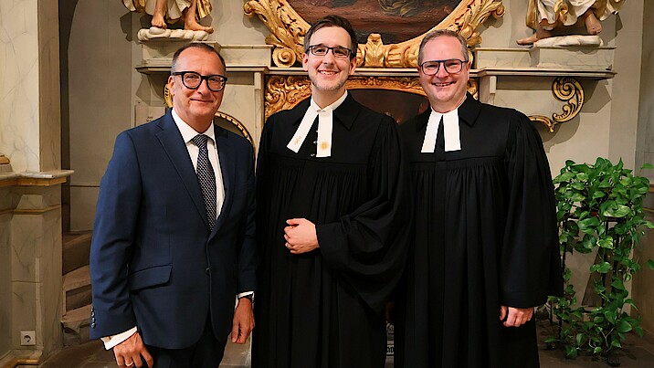 Dietmar Prexl, Dr. Friedemann Kuttler und Pfarrer Jakob Fuchs stehen nebeneinander in der Kirche.