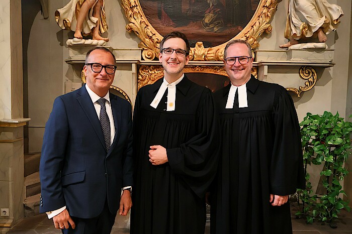 Dietmar Prexl, Dr. Friedemann Kuttler und Pfarrer Jakob Fuchs stehen nebeneinander in der Kirche.