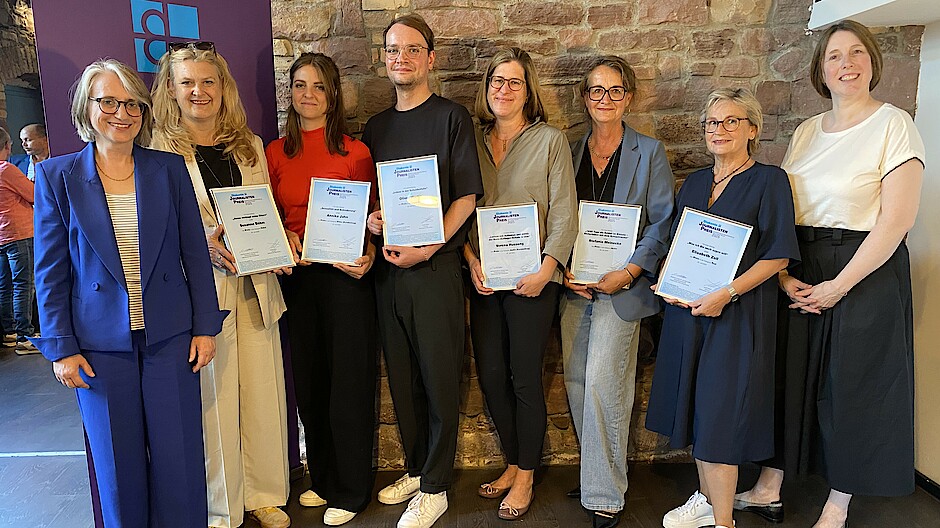 Die Gewinnerinnen und Gewinner des Diakonie Journalistenpreis 2025 stehen eingerahmt von den Vorständinnen der Diakonischen Werke Württemberg und Baden mit ihren Urkunden in der Hand vor einer Wand und lachen in die Kamera.