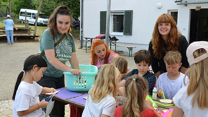 Zwei Frauen stehen mit Kindern am Tisch bei einem Bastelangebot zum Thema „Abenteuer auf hoher See“.