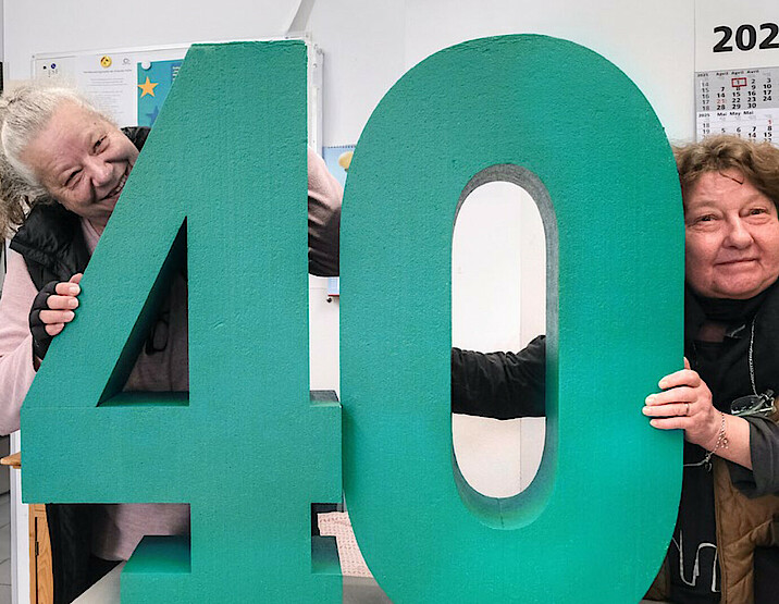 Zwei Frauen umarmen eine große Zahl 40