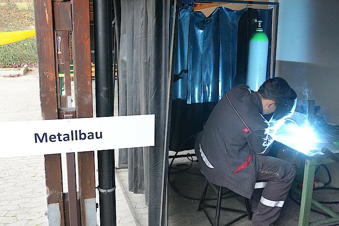 Eine männliche Person schweißt an einem Tisch im Metallbau.