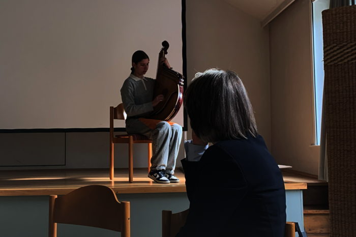 Eine junge Ukrainerin spielt ein Saiteninstrument, Annette Noller hört zu.