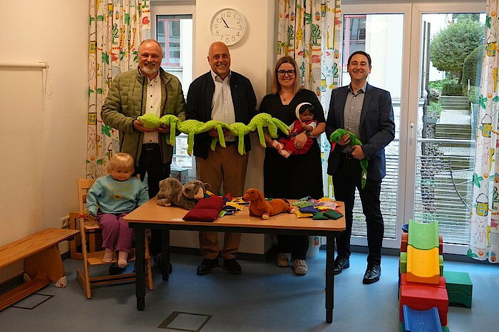 Vier Personen haben Kuscheltiere in der Hand und lächeln in die Kamera